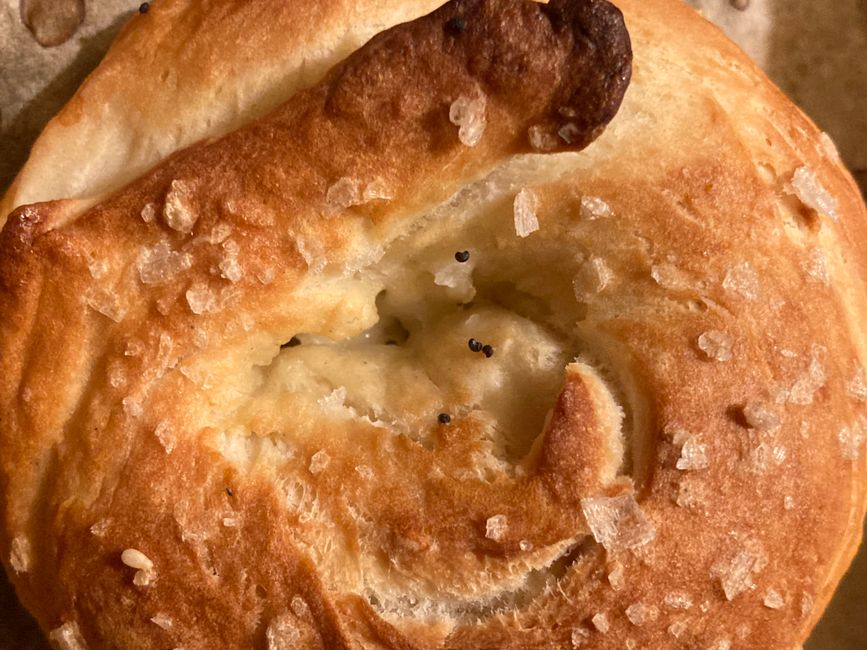 Golden-brown baked pretzel topped with coarse salt offers a close-up view of texture and detail.